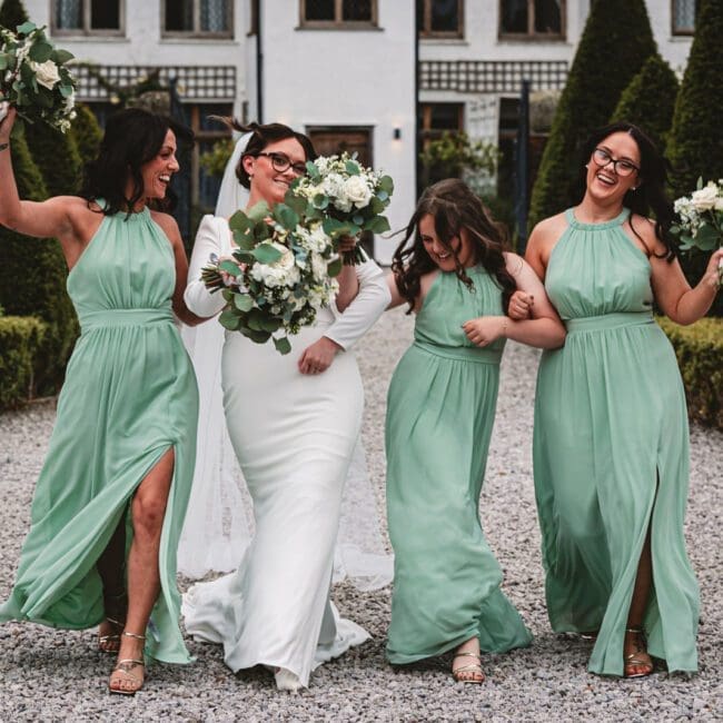 bridesmaids in pale green bridesmaid dresses walking with bride in middle at riverbarn poulton