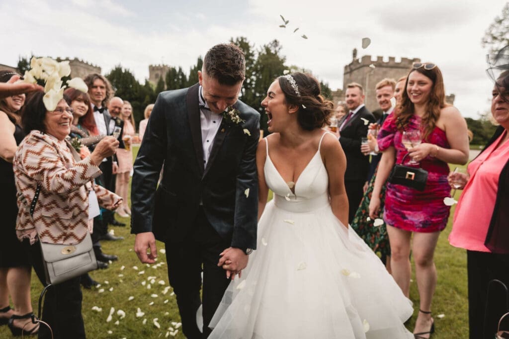 A confetti throw as the bride and groom walk past at Ripley Castle
