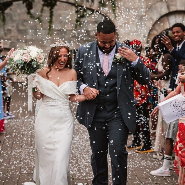 White conffeti being thrown at hazzlewood castle as the bride and groom walk through | as a west Yorkshire wedidng