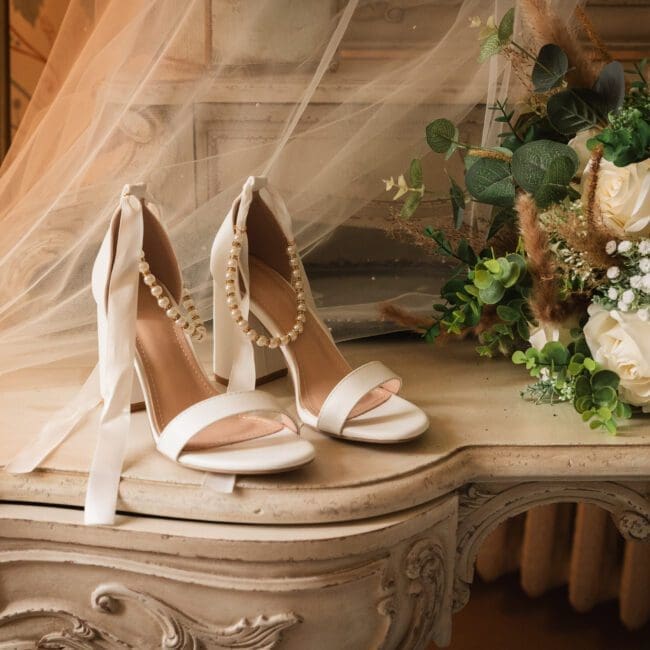 Jess & Alex – 2011 Brides shoes on a vanity table with her veil behind in the bridal prep room at hodsock priory | Hodsock priory wedding photographer