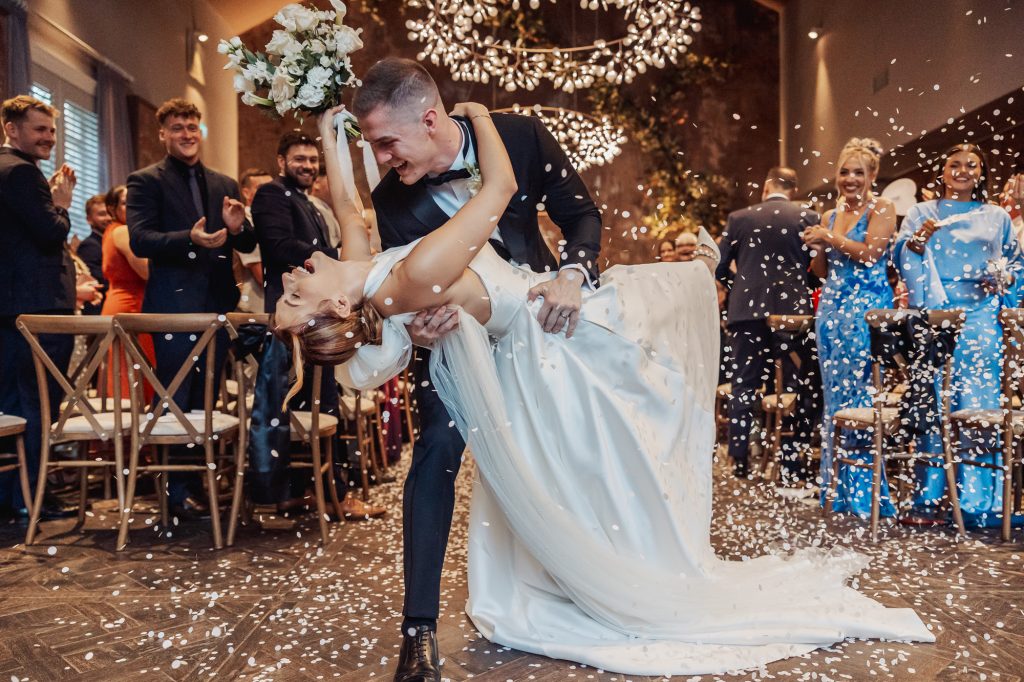 A bride being dipped with conffeti around here at the manor house lindley taken by a yorkshire wedding photographer