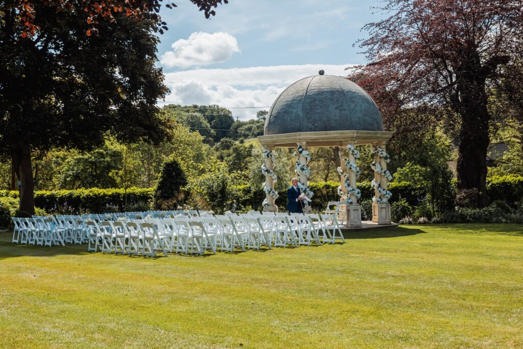 The stone pavilion at Wentbridge House Hotel set for an outdoor ceremony, with rows of white chairs and the wooded valley beyond.