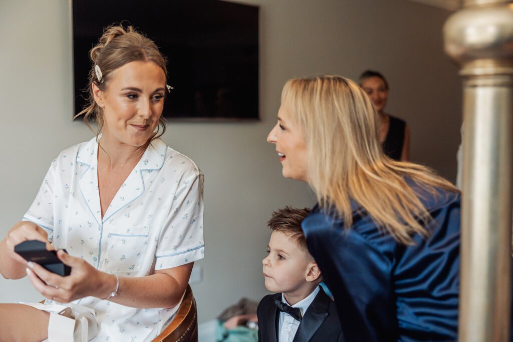 The bride shares a gift with her mother and page boy during preparations at Wentbridge House Hotel.