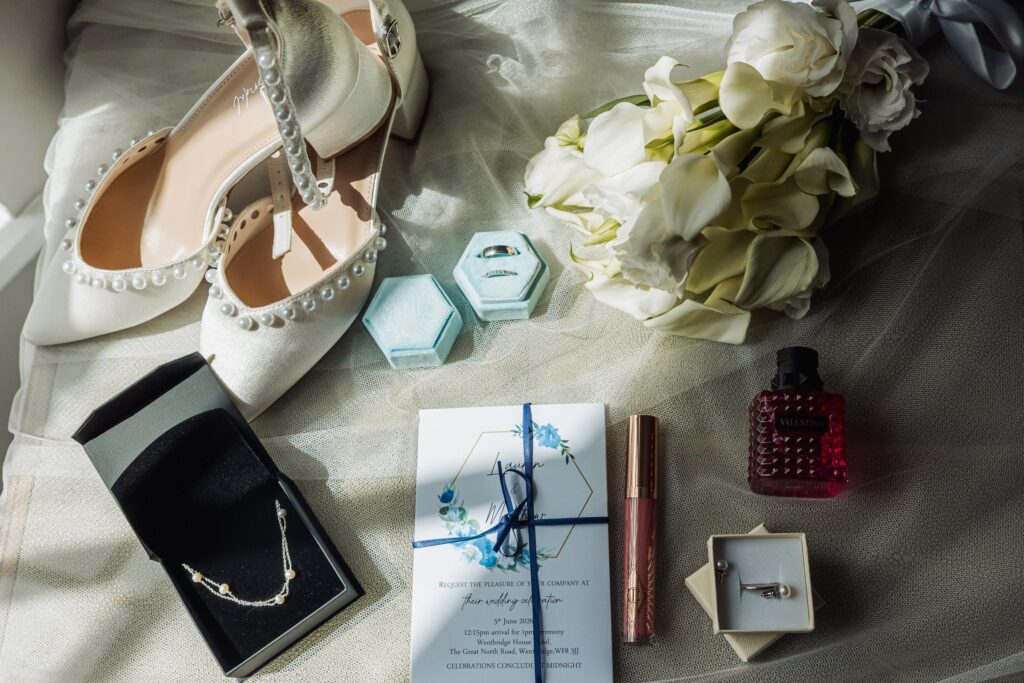 Wedding day details laid out together, including the rings, perfume and the invitation to Wentbridge House Hotel.