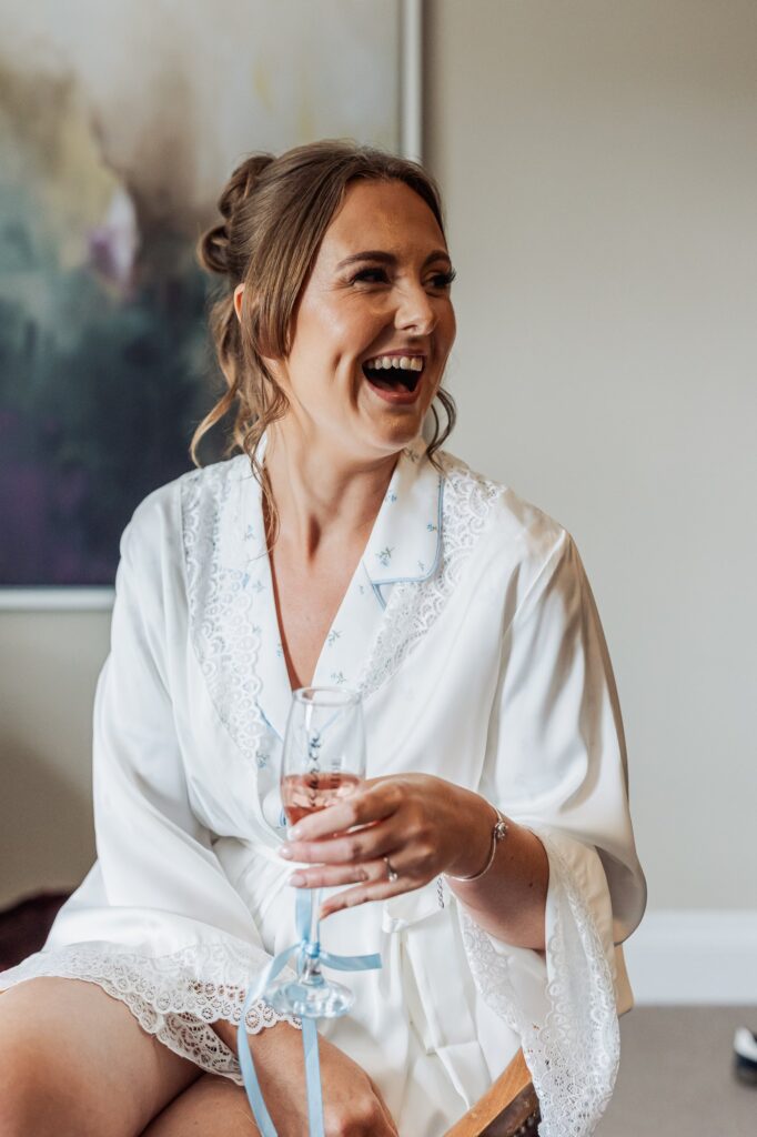 The bride laughs with her bridesmaids while getting ready at Wentbridge House Hotel.