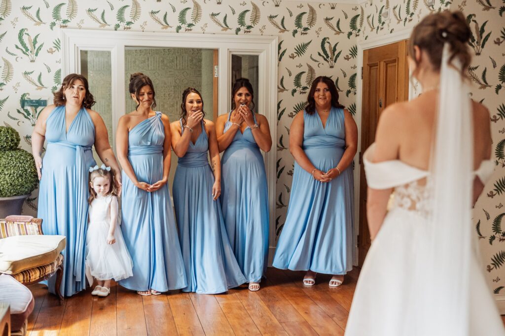 The bridesmaids in pale blue see the bride in her dress for the first time.