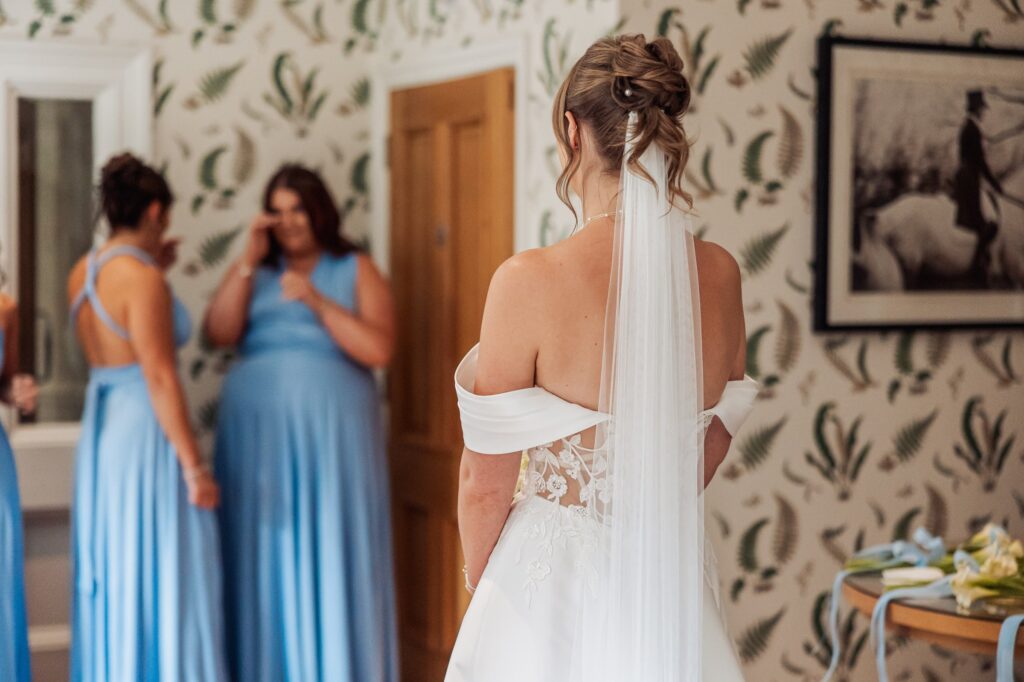 The bride photographed from behind, her veil falling the full length of the lace-backed gown.