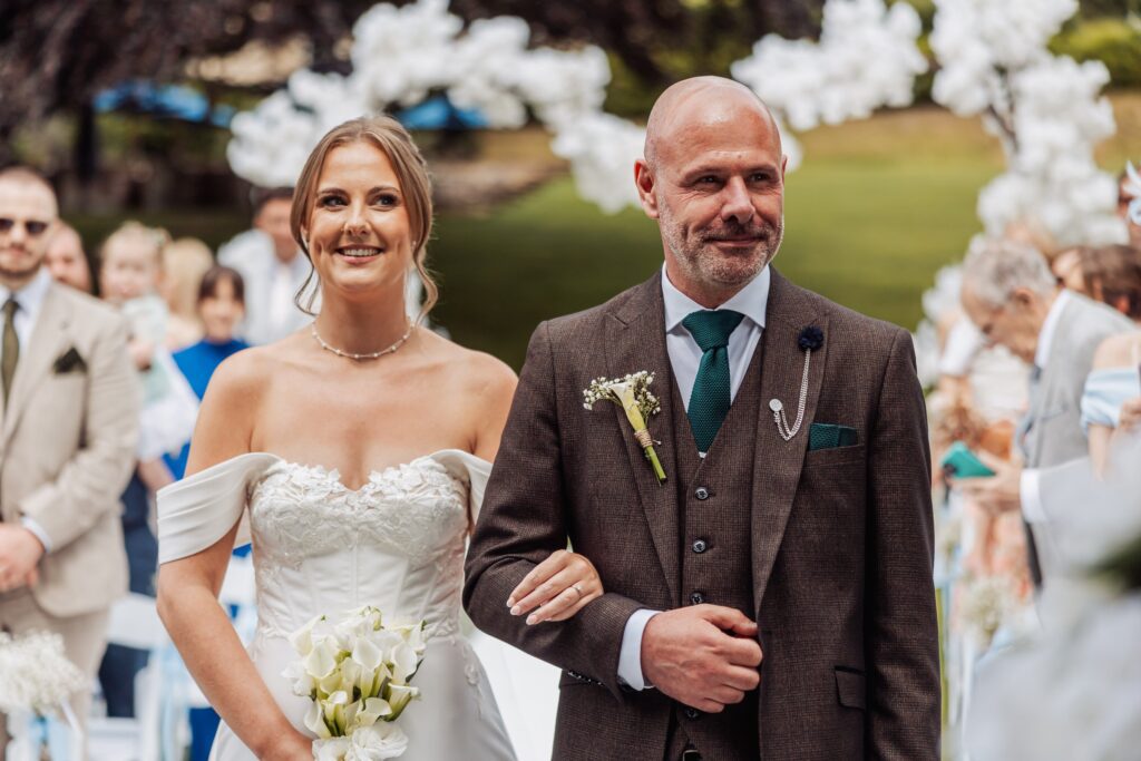 The bride and her father share the walk down the aisle on a summer afternoon in West Yorkshire.