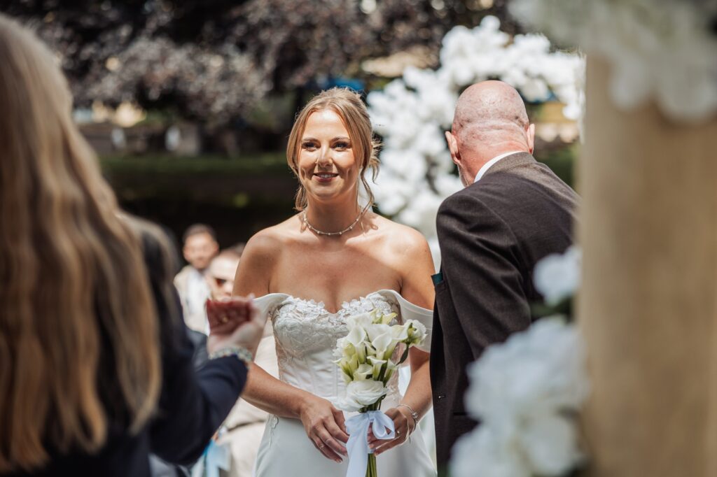 The bride arrives at her outdoor ceremony as guests turn to watch.