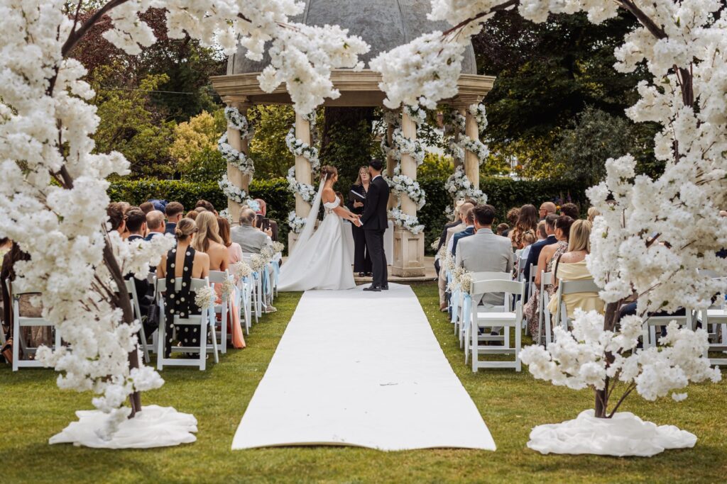 The ceremony framed by white blossom trees and the domed stone pavilion at Wentbridge House Hotel.