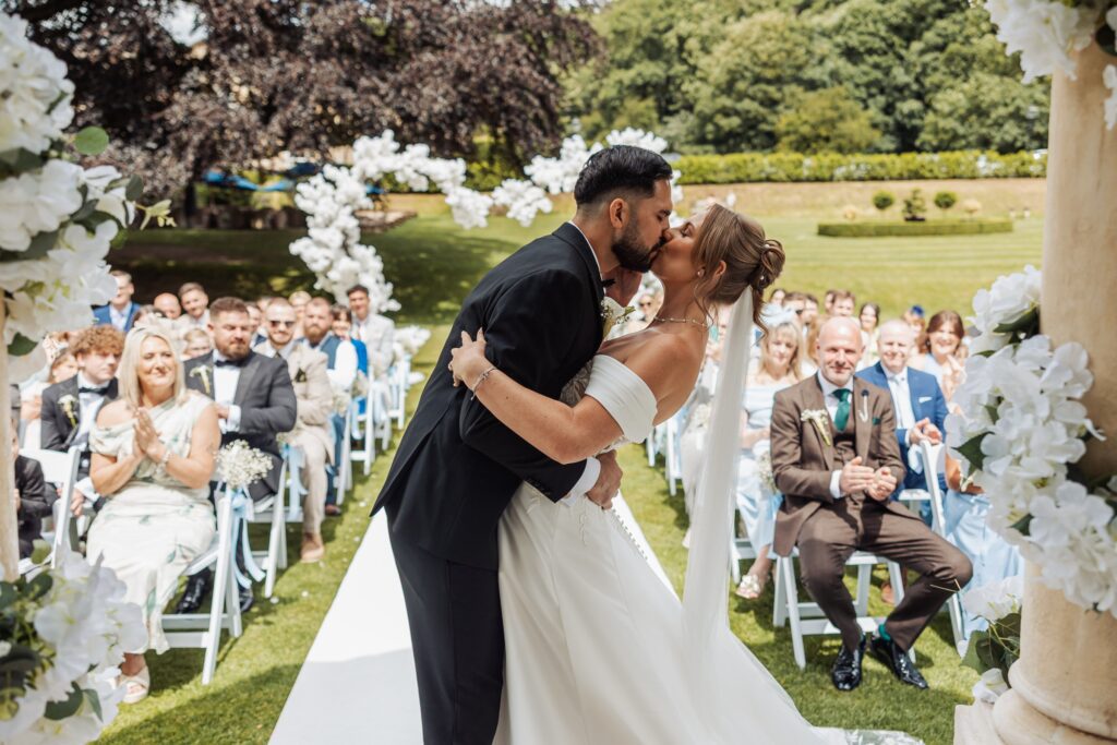 The first kiss as husband and wife beneath the stone pavilion at Wentbridge House Hotel.