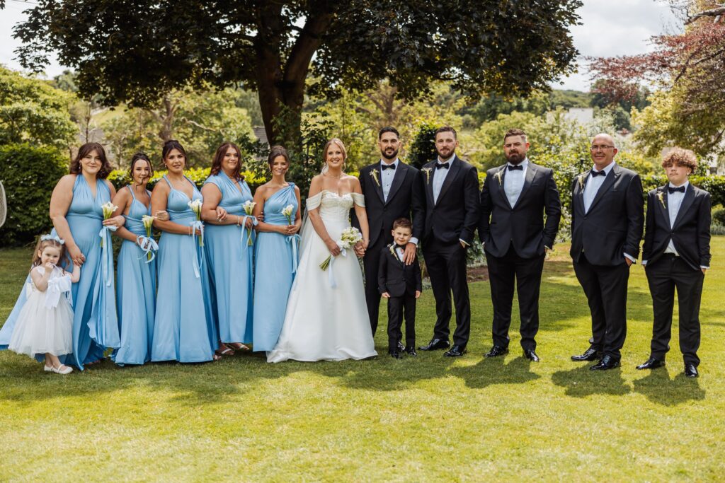 The bride with her bridesmaids in pale blue, holding calla lily bouquets.