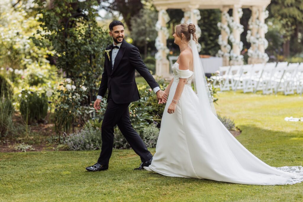 Bride and groom walk hand in hand past the ceremony pavilion at Wentbridge House Hotel.