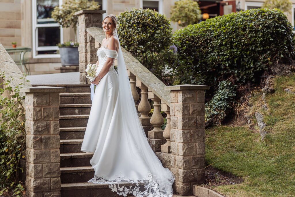 Bridal portrait on the stone steps of Wentbridge House Hotel, her veil spilling down behind her.