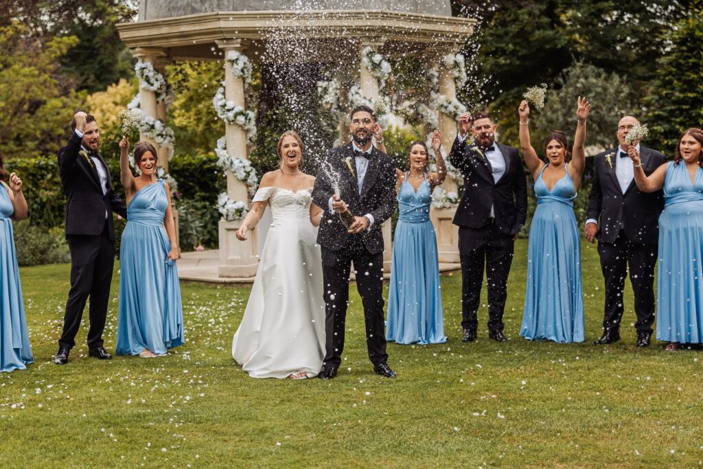 Champagne sprays over the bridal party on the lawn at Wentbridge House Hotel.