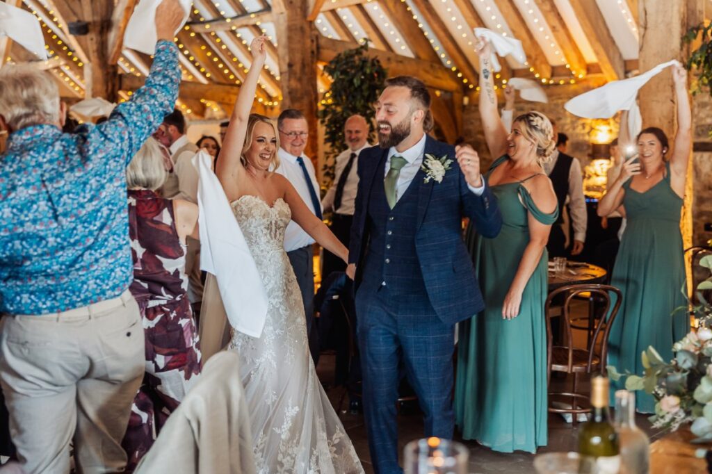 Bride and groom arrive at the wedding breakfast at Tithe Barn Bolton Abbey to a napkin-waving welcome from their guests.