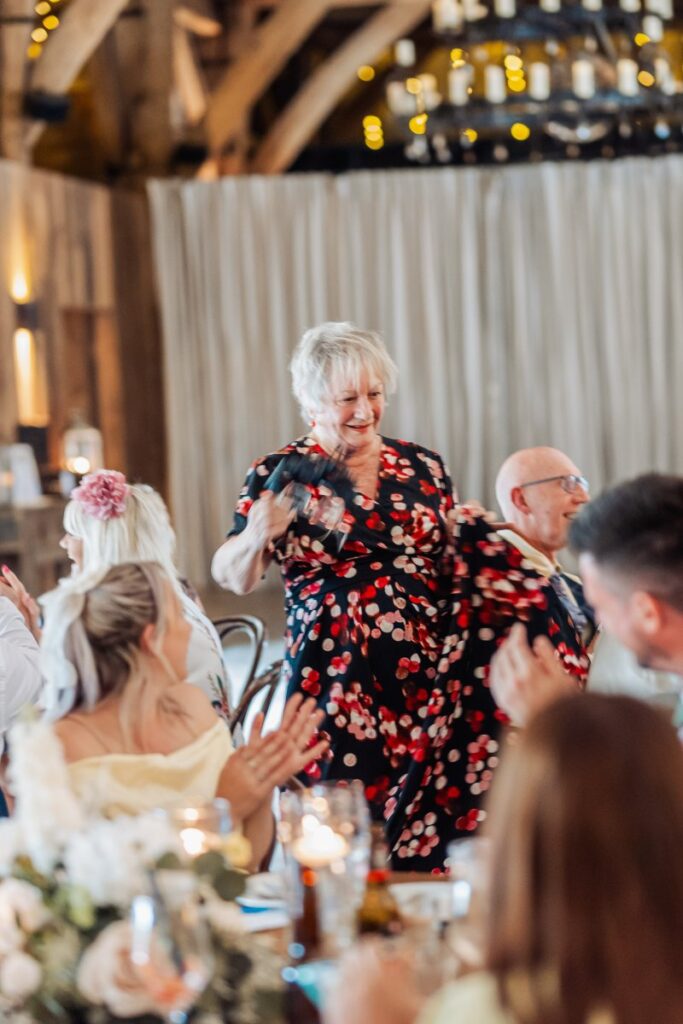 A guest dances between the tables at Tithe Barn Bolton Abbey as the room claps along.