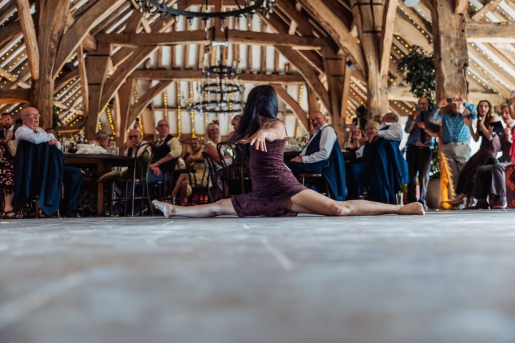 A guest drops into the splits on the dance floor at Tithe Barn Bolton Abbey while the room watches.