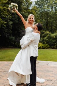 A couple in wedding attire, the woman in a strapless white gown and the man in a white suit jacket and black trousers at Woodlands Hotel, Leeds