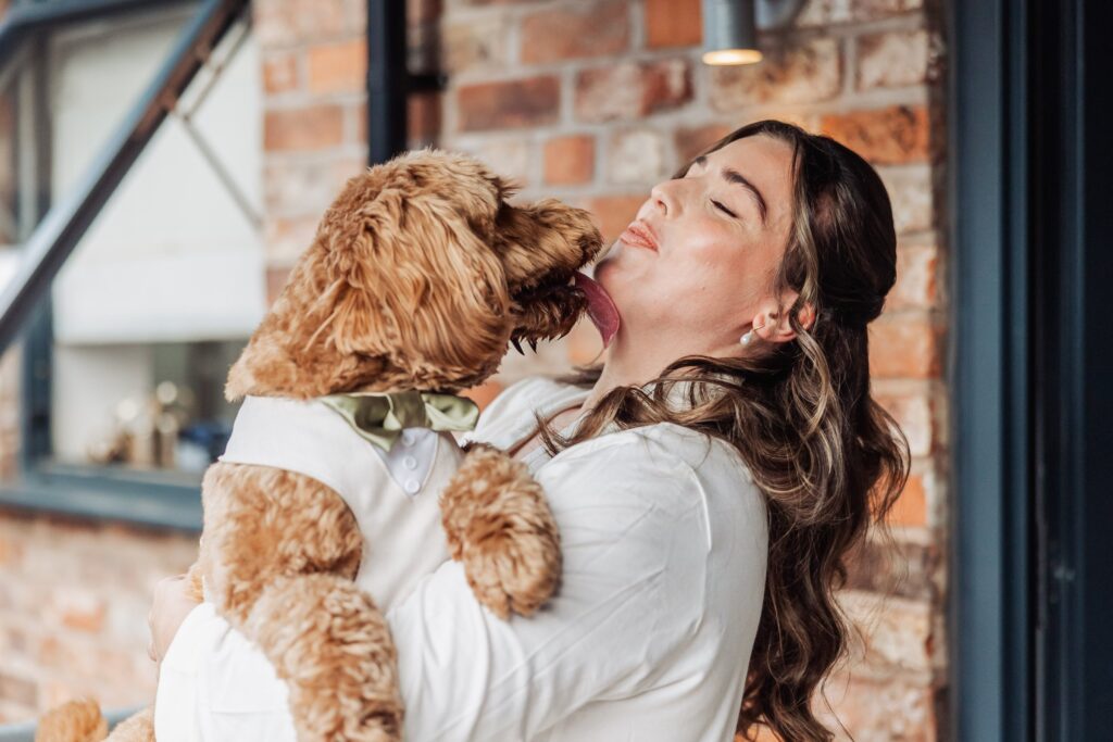 A woman in a white shirt holds a small, fluffy dog wearing a green bow tie at Autumn & Sam - Owen house barn
