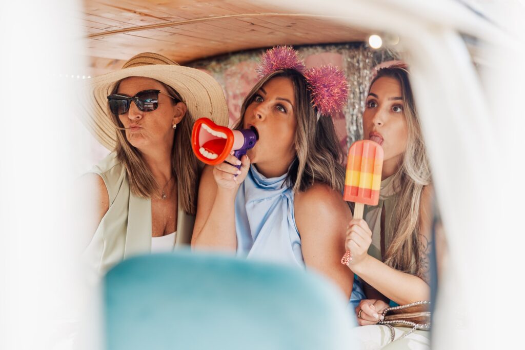 Three women pose for a photo, one holding a toy megaphone, another a colourful popsicle at Autumn & Sam - Owen house barn