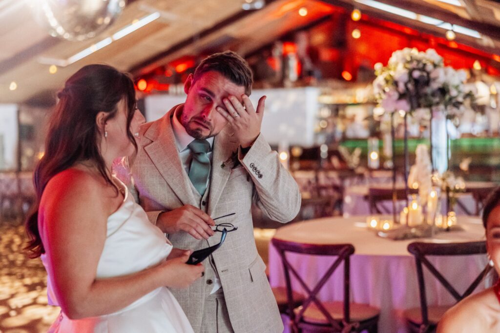 A couple in wedding attire, the man in a light suit and the woman in a white dress at Autumn & Sam - Owen house barn