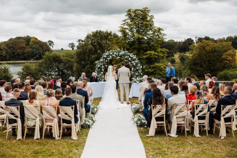 A wedding ceremony is taking place outdoors with a couple standing at the altar, facing each other at Coniston Hotel, Skipton