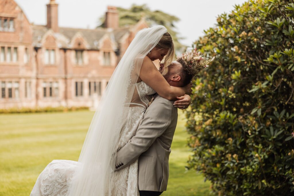 Bride and groom kissing beside the magnolia on the lawn at Colshaw Hall