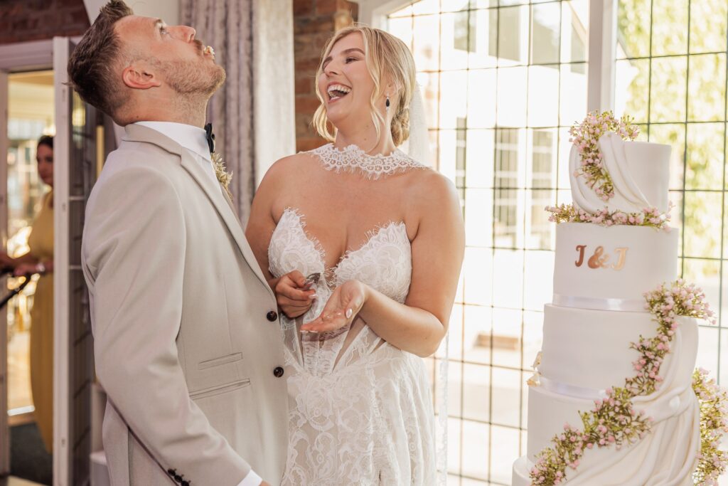 A couple in wedding attire stands close together, smiling and laughing at Colshaw Hall, Cheshire
