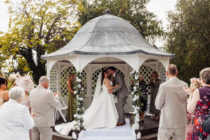 Outdoor wedding ceremony on the lawn at Hodsock Priory with guests seated on white chairs