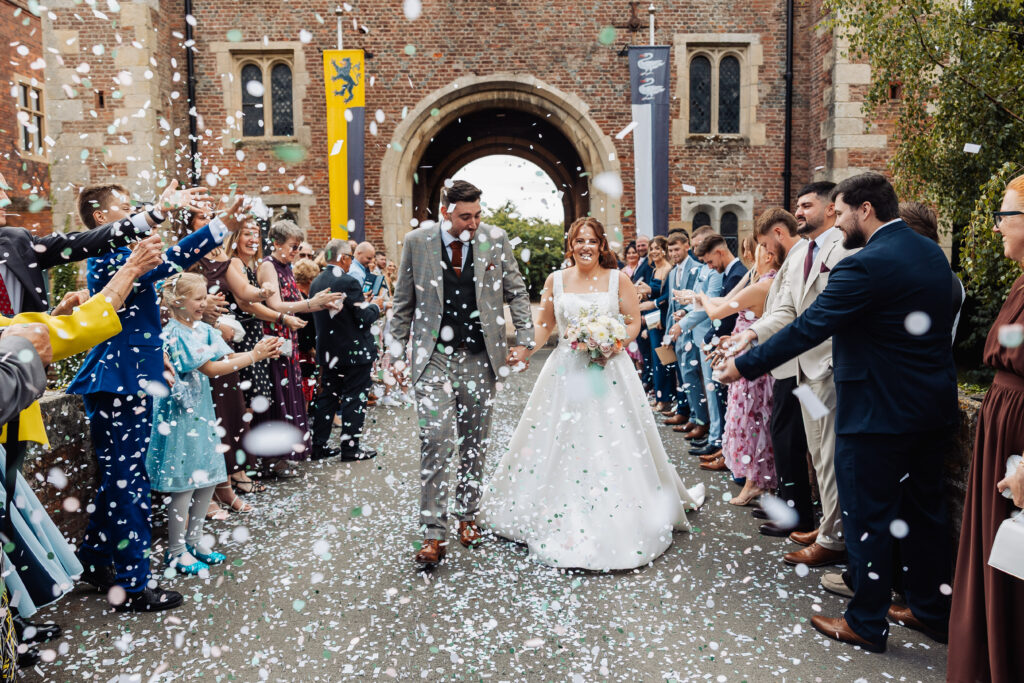 Confetti thrown over the bride and groom as they walk the path outside Hodsock Priory