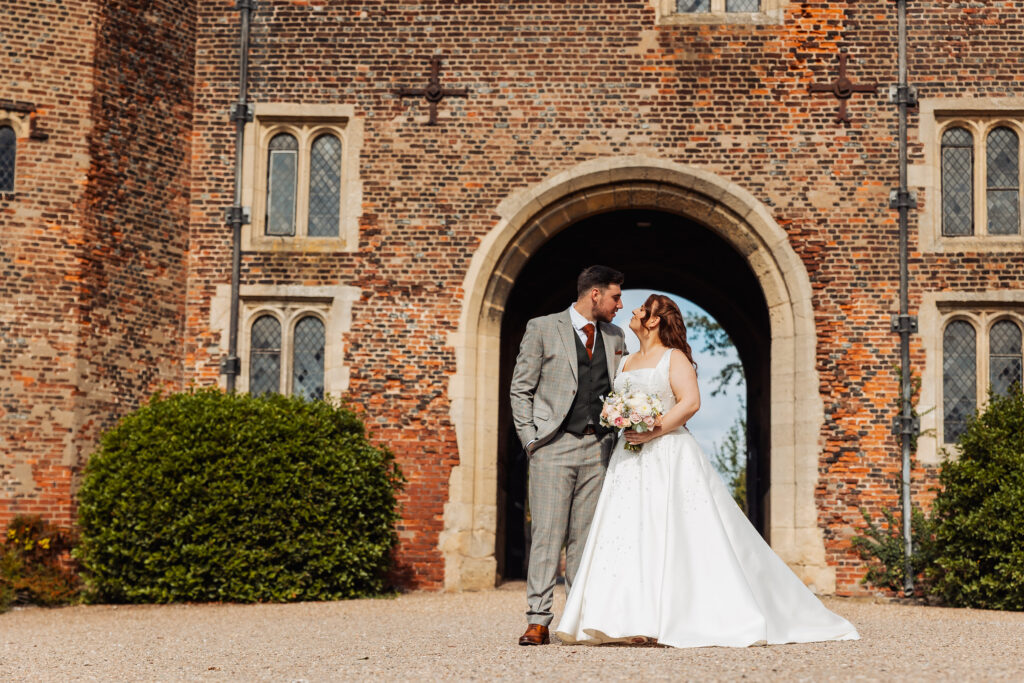 Bride and groom kiss framed by the Tudor gatehouse archway at Hodsock Priory