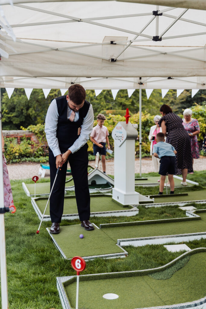 Wedding guests playing crazy golf on the lawn at Hodsock Priory between the meal and the evening