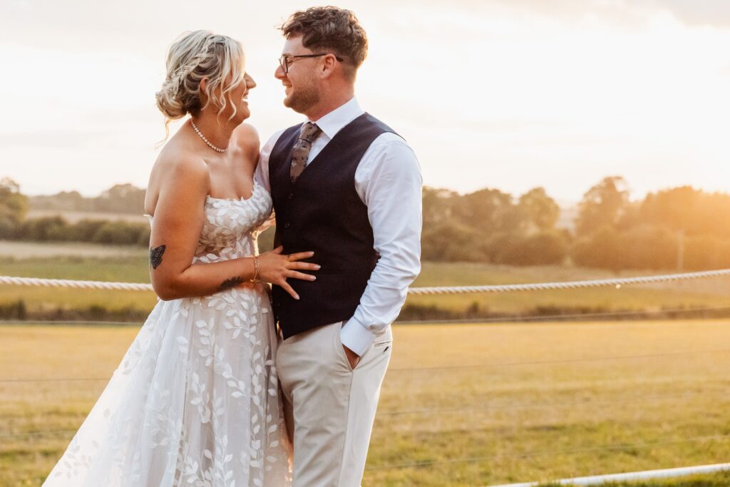 Bride and groom embracing in the farmland at golden hour at Sedgewell Barn