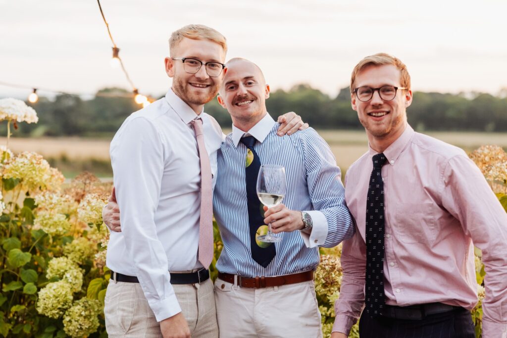 Three wedding guests with drinks outside during the reception at Sedgewell Barn