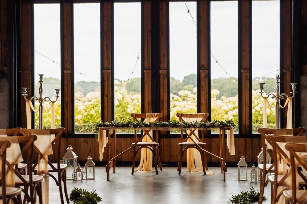 The Celebration Barn at Sedgewell Barn set for the ceremony, chairs and candles beside the glass wall