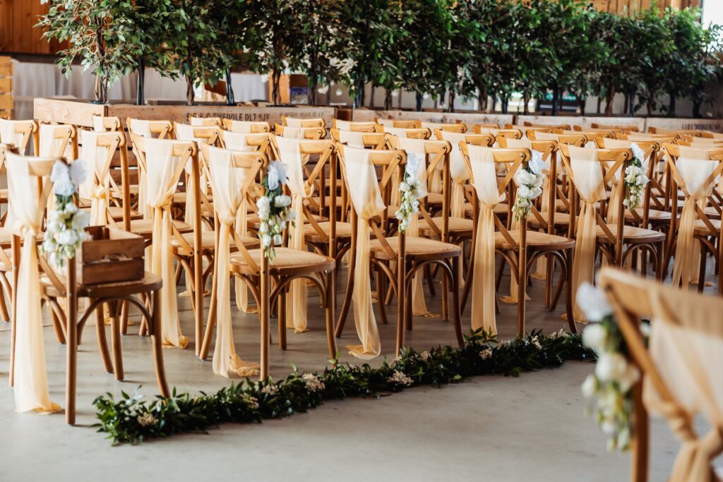 Rows of chairs dressed with sashes and florals before the ceremony at Sedgewell Barn