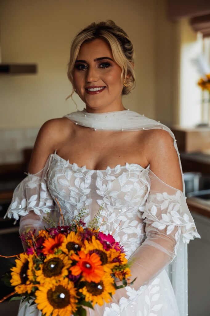 Bride holding her sunflower and orange bouquet before the ceremony at Sedgewell Barn