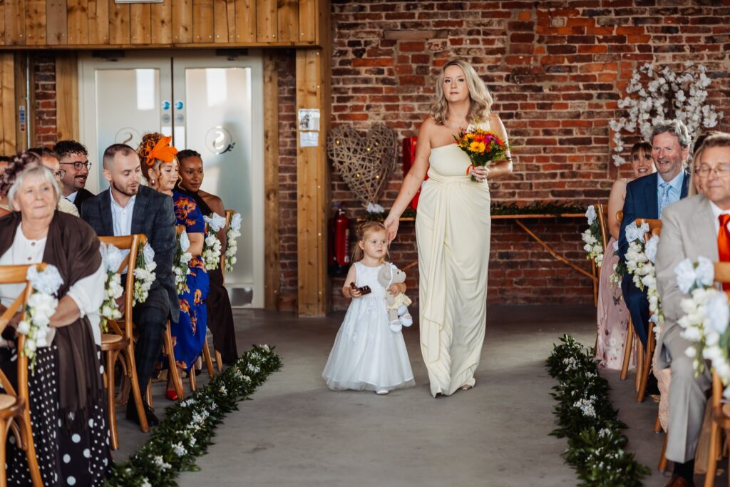 Bridesmaid and flower girl walking down the aisle at Sedgewell Barn