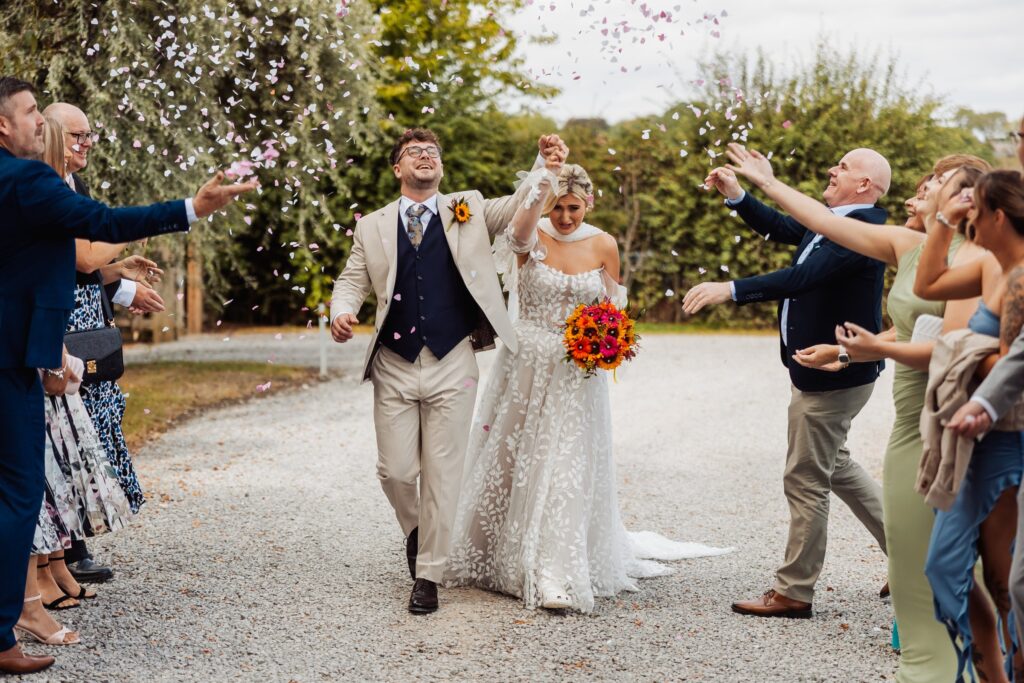 Bride and groom walking through the confetti line outside Sedgewell Barn