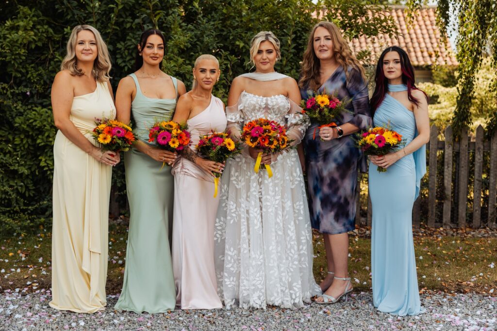 Bridesmaids lined up with bright sunflower and orange bouquets at Sedgewell Barn