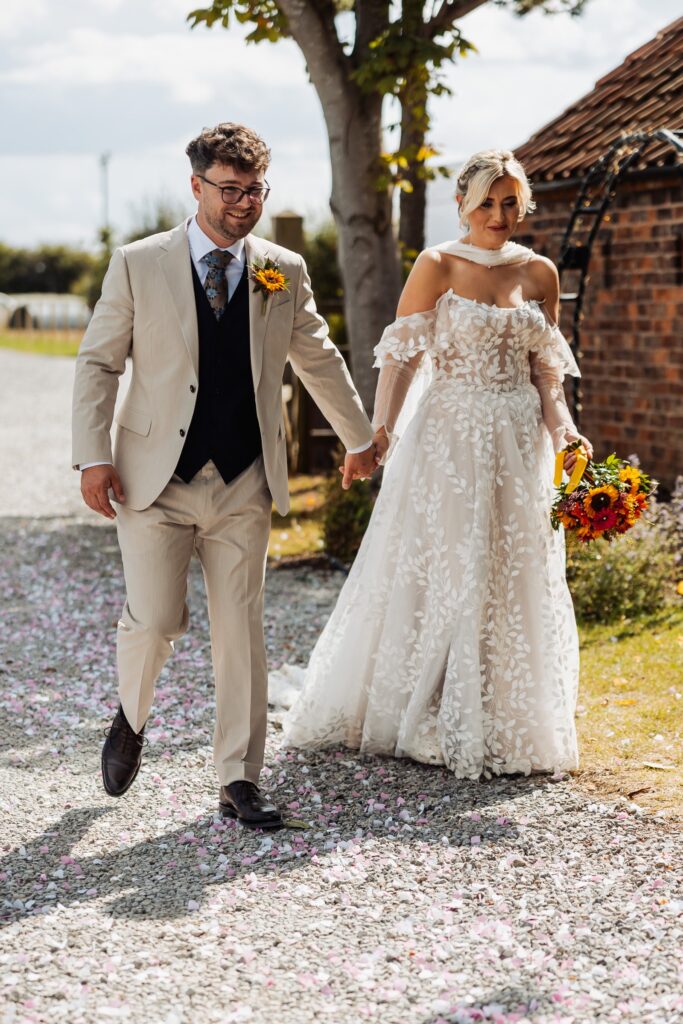 Bride and groom walking hand in hand past the barn at Sedgewell Barn