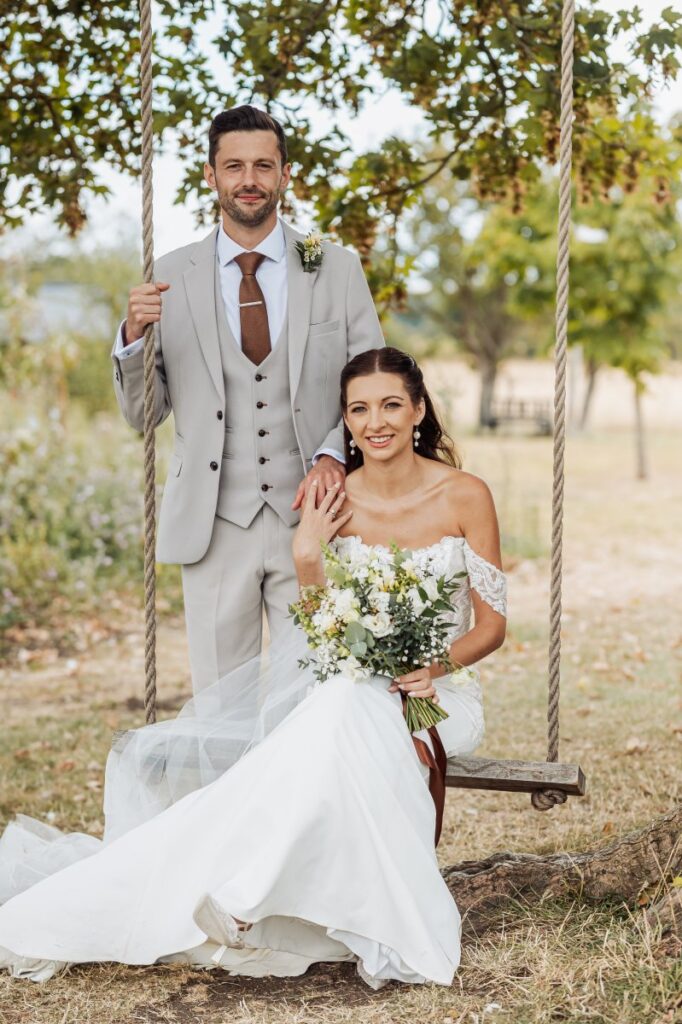 Bride and groom at the rope swing beneath the oak tree at Clayfield Farm.
