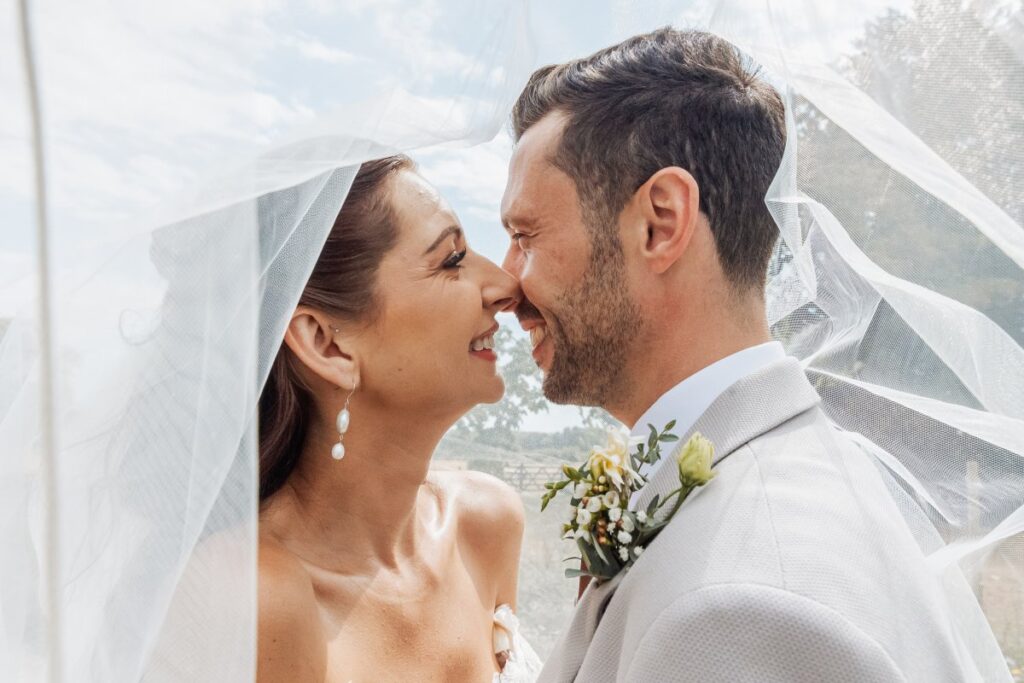 A kiss beneath the sweeping veil, with the trees of the Yorkshire Wolds behind.