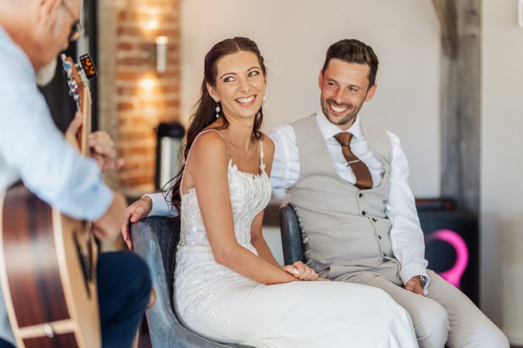The bride and groom laugh together as live music plays during their Clayfield Farm reception.
