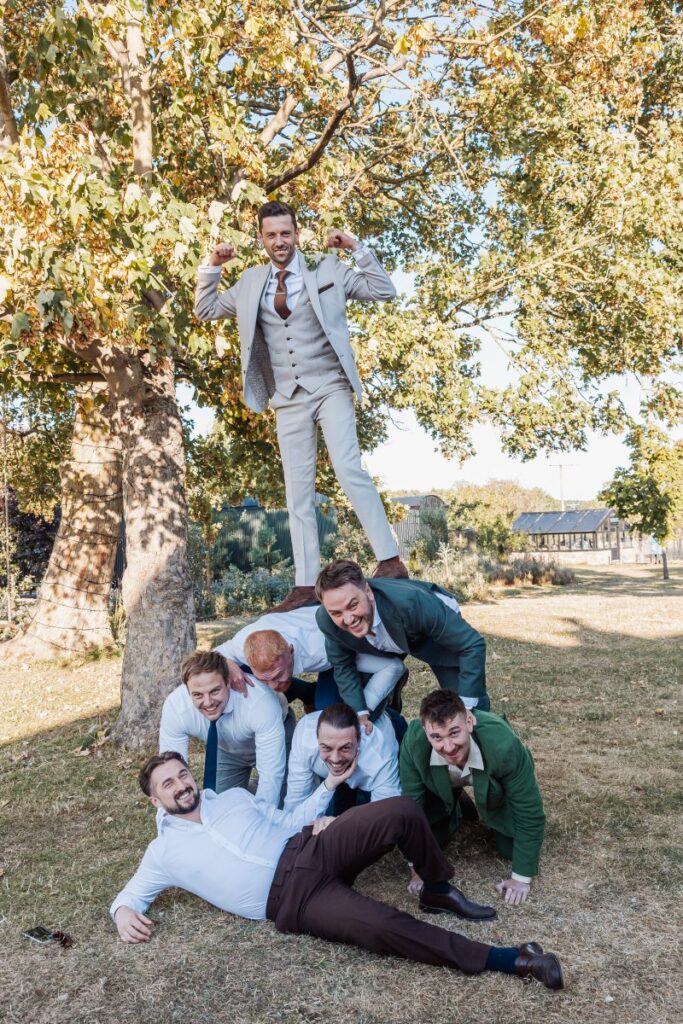 The groomsmen build a human pyramid under the trees at Clayfield Farm.